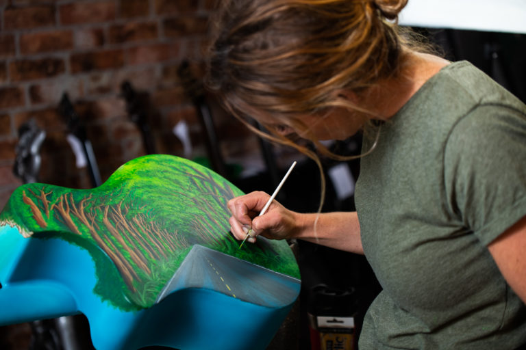 Jessica hand painting an Emerald Guitar
