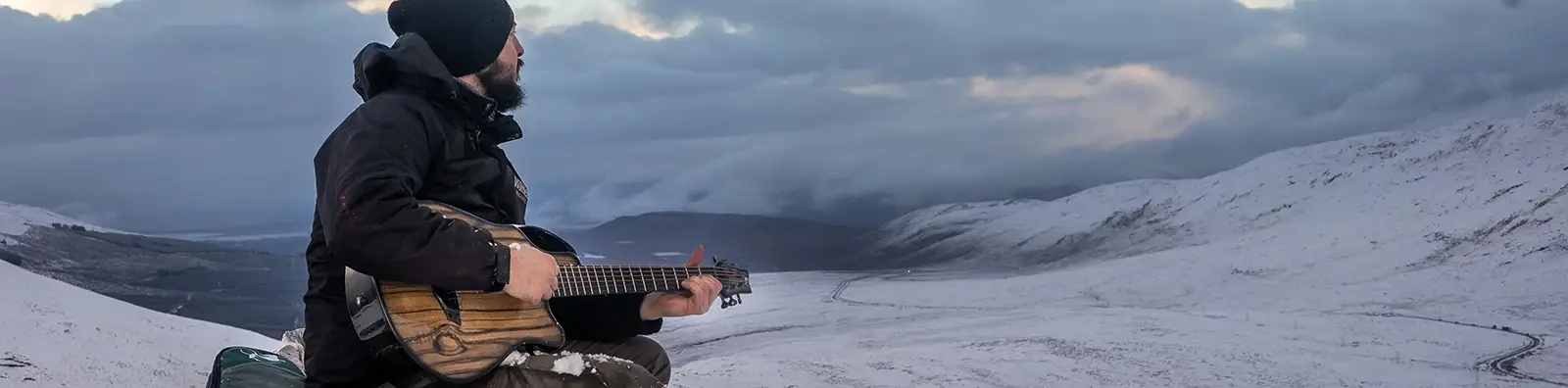 Man Playing Emerald Guitar on a snowy mountaintop