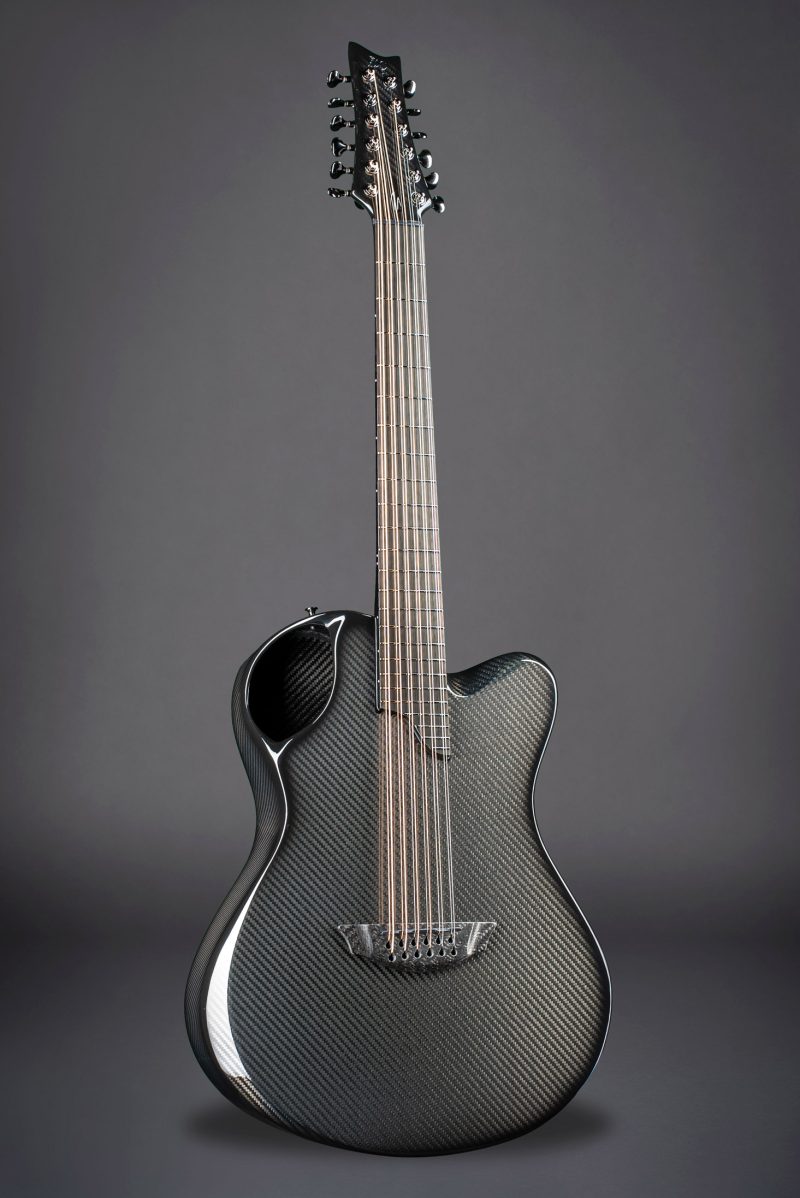 Emerald X20 12-string guitar in black carbon fiber against dark background