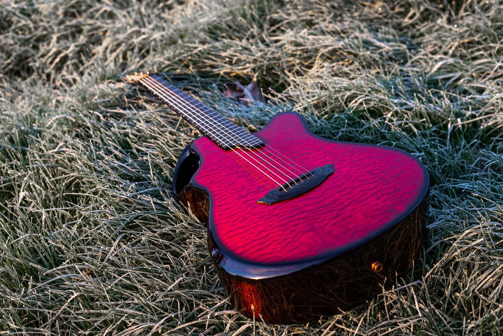 A red Emerald Guitar laying flat on frosty grass